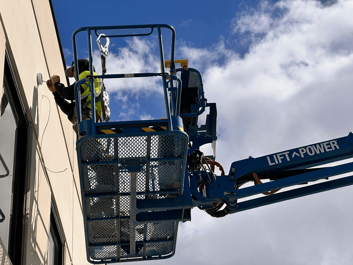 LVEC technician on a boom lift mounting a camera on a building exterior