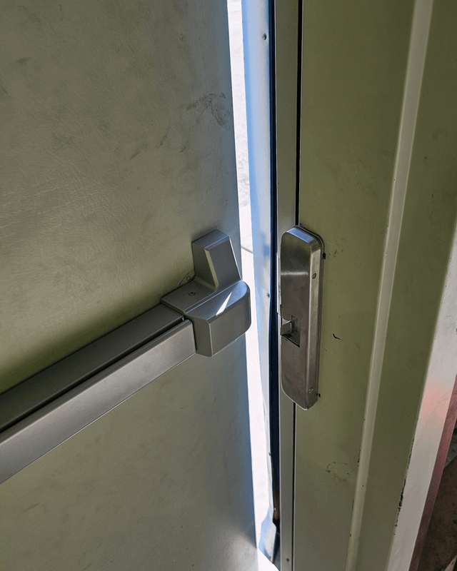 Exit bar and electric strike installed on a commercial steel door